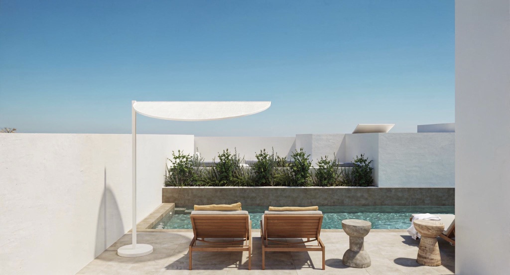 A plunge pool beneath a cantilevered shade sail, with grey loungers and concrete side tables.